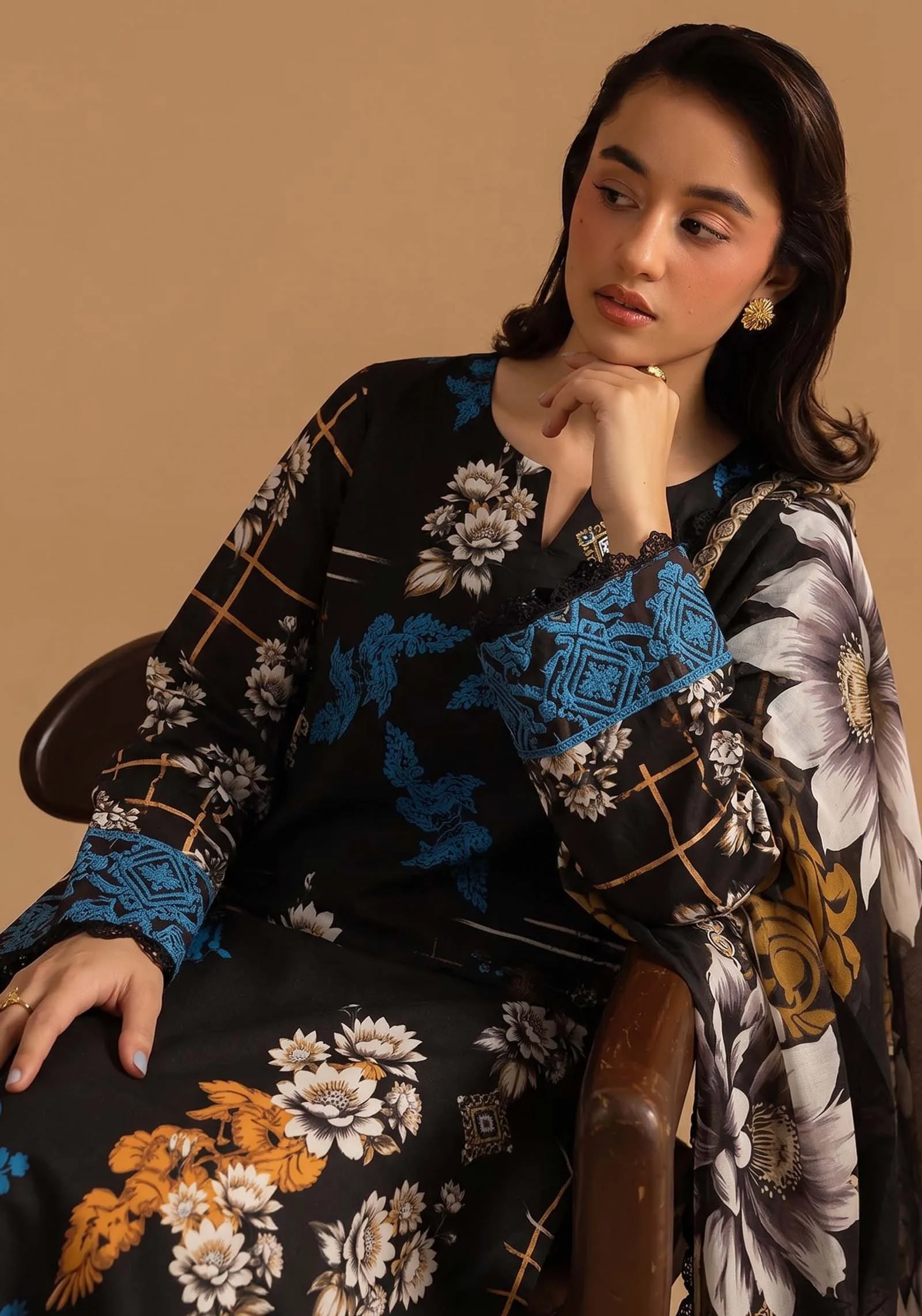 Detail of blue embroidery on sleeve and floral motifs on black fabric